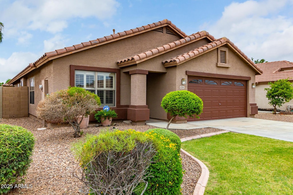 mediterranean / spanish house featuring driveway, an attached garage, and stucco siding