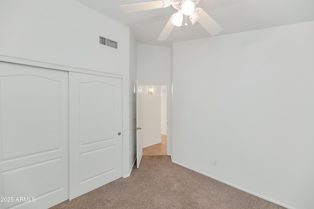 unfurnished bedroom featuring ceiling fan, a closet, and light carpet