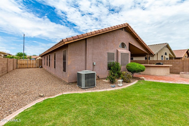 rear view of house with a patio, central AC unit, and a yard