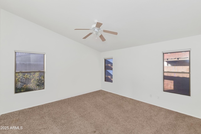 empty room with vaulted ceiling, ceiling fan, a wealth of natural light, and carpet