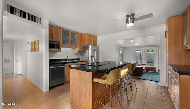 7543 E Portland St, Scottsdale, AZ 85257 - kitchen with appliances with stainless steel finishes, a kitchen island, a breakfast bar, ceiling fan, and glass insert cabinets