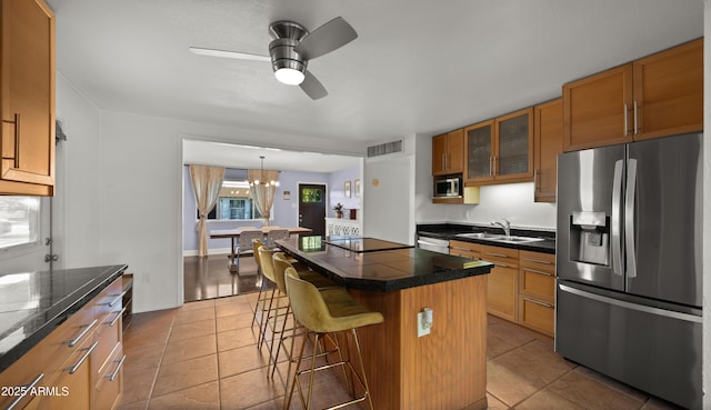 7543 E Portland St, Scottsdale, AZ 85257 - kitchen featuring stainless steel appliances, a breakfast bar, glass insert cabinets, ceiling fan, and brown cabinets