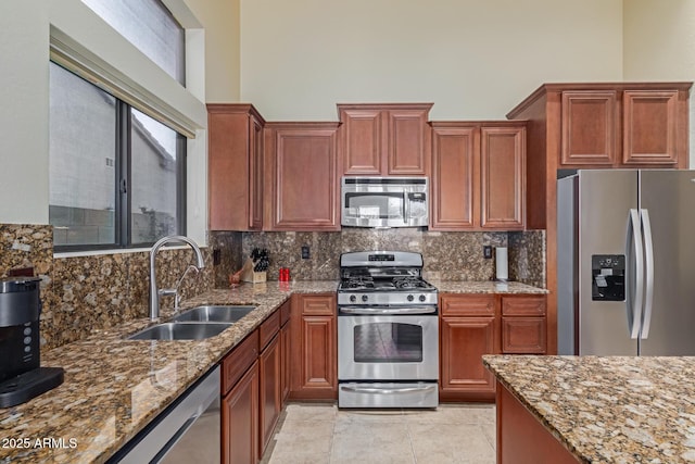 kitchen featuring tasteful backsplash, appliances with stainless steel finishes, light stone countertops, and sink