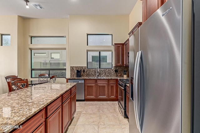 kitchen featuring light stone counters, sink, tasteful backsplash, and appliances with stainless steel finishes