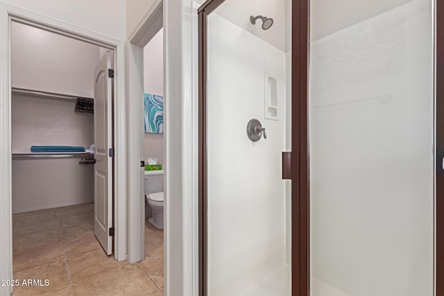 bathroom featuring toilet, an enclosed shower, and tile patterned flooring