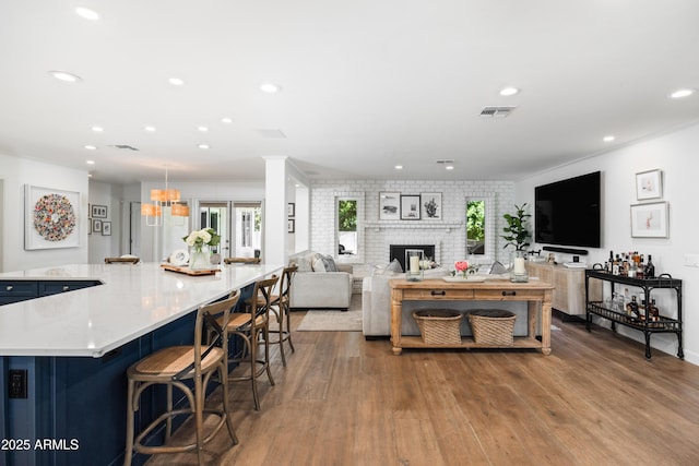 living room featuring a brick fireplace, plenty of natural light, and light hardwood / wood-style flooring