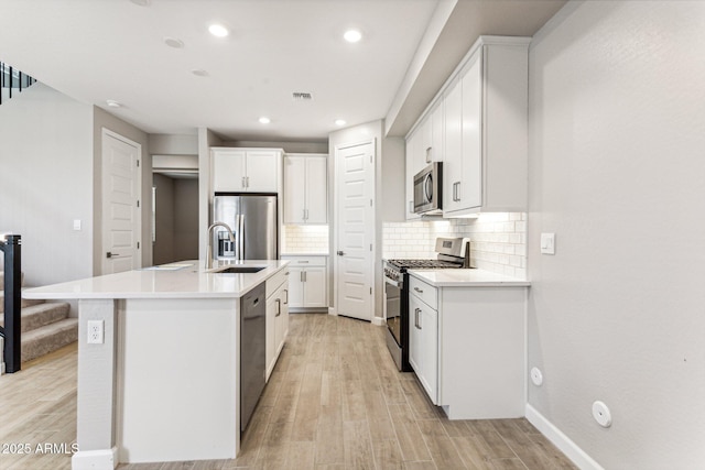 21228 N 58th St, Phoenix, AZ 85054 - kitchen with stainless steel appliances, light wood-style floors, tasteful backsplash, white cabinetry, and recessed lighting