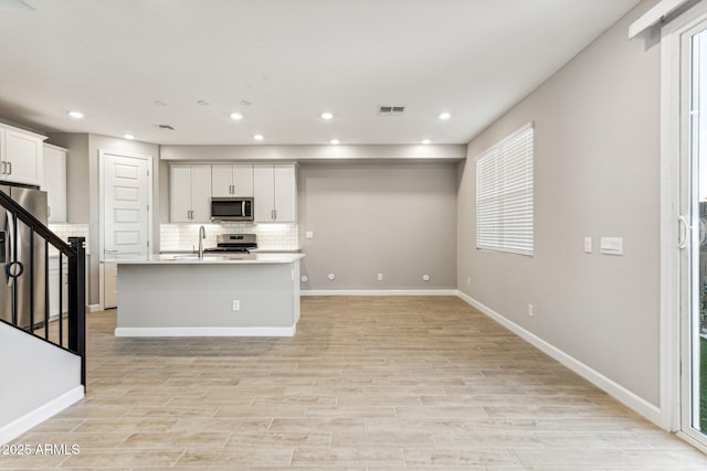 21228 N 58th St, Phoenix, AZ 85054 - kitchen featuring appliances with stainless steel finishes, decorative backsplash, a sink, an island with sink, and recessed lighting