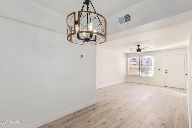 spare room featuring light hardwood / wood-style floors and ceiling fan with notable chandelier