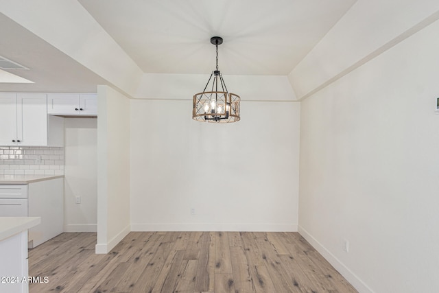 unfurnished dining area featuring light wood-type flooring and a notable chandelier