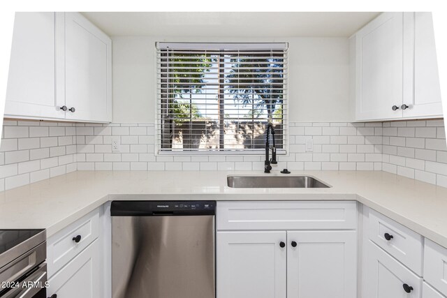 kitchen with tasteful backsplash, stainless steel dishwasher, sink, and white cabinets