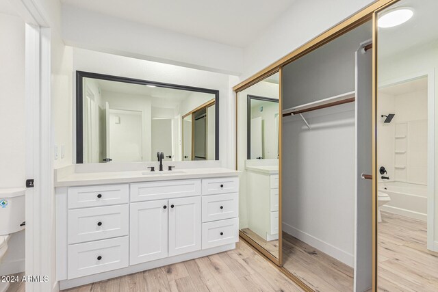 full bathroom with toilet, washtub / shower combination, vanity, and hardwood / wood-style floors