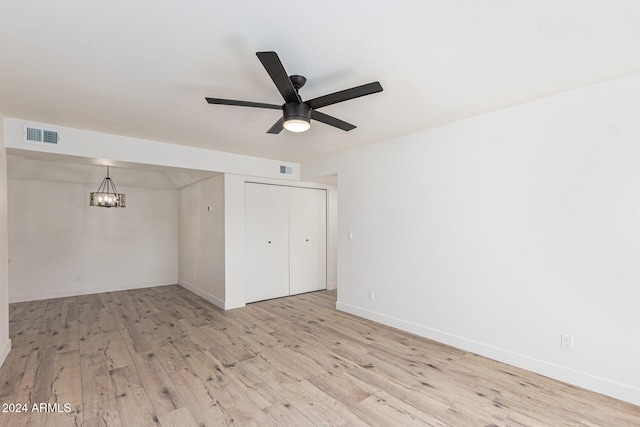 interior space featuring light wood-type flooring, ceiling fan with notable chandelier, and a closet