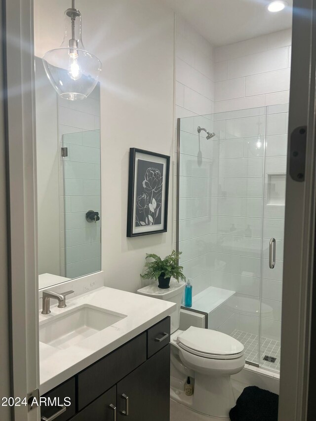 bathroom with tile patterned floors, vanity, toilet, and a shower with shower door