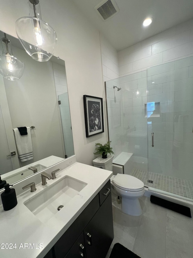 bathroom featuring tile patterned flooring, a shower with door, vanity, and toilet