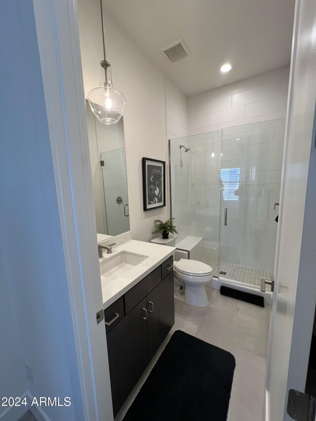 bathroom with tile patterned flooring, vanity, toilet, and a shower with door