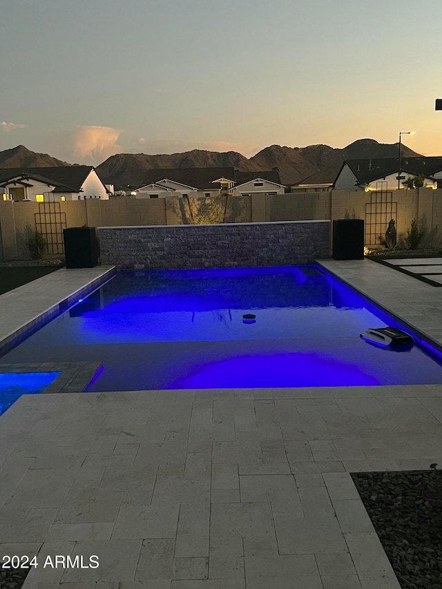 pool at dusk featuring a mountain view and a patio area