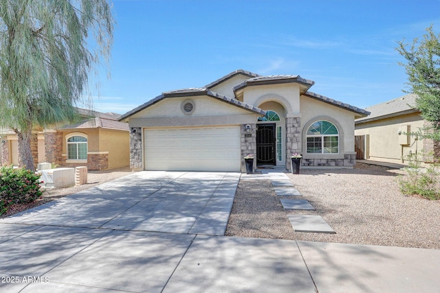 2716 W Sunland Ave, Phoenix, AZ 85041 - mediterranean / spanish house featuring stone siding, stucco siding, an attached garage, driveway, and a tile roof