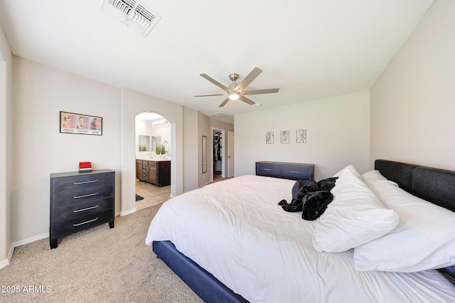 2716 W Sunland Ave, Phoenix, AZ 85041 - bedroom featuring arched walkways, light carpet, connected bathroom, a ceiling fan, and baseboards