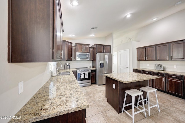 2716 W Sunland Ave, Phoenix, AZ 85041 - kitchen with appliances with stainless steel finishes, a sink, vaulted ceiling, dark brown cabinetry, and a center island