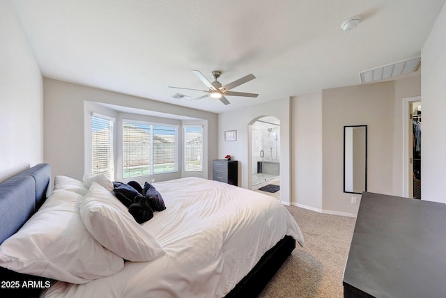 2716 W Sunland Ave, Phoenix, AZ 85041 - carpeted bedroom featuring arched walkways, a ceiling fan, a walk in closet, ensuite bathroom, and baseboards