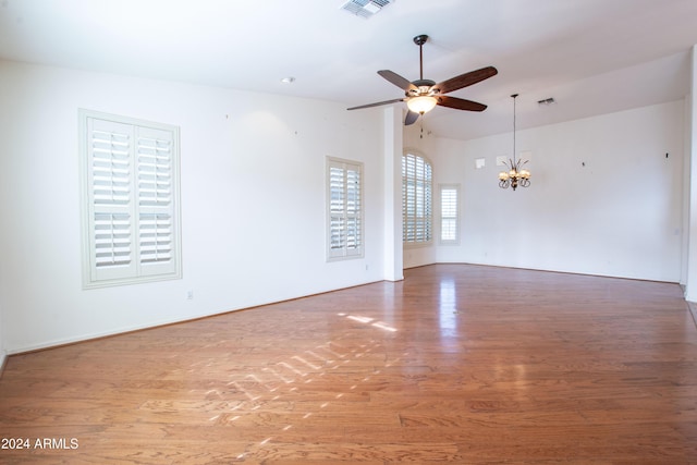 unfurnished room featuring visible vents, ceiling fan with notable chandelier, and wood finished floors