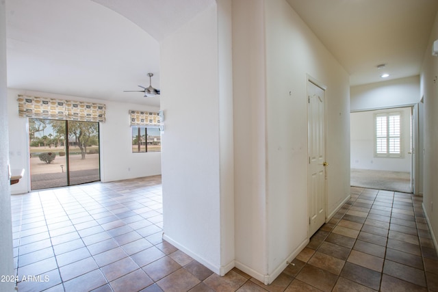 hall with arched walkways and tile patterned floors