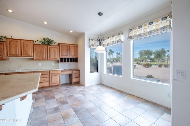 kitchen with built in study area, lofted ceiling, recessed lighting, decorative light fixtures, and backsplash