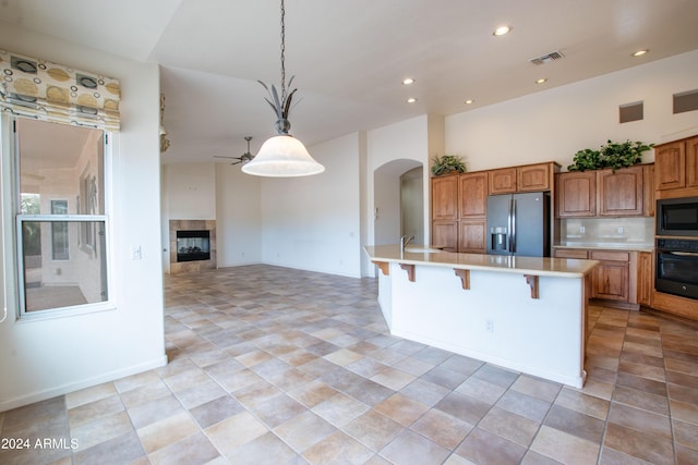 kitchen with oven, visible vents, stainless steel refrigerator with ice dispenser, light countertops, and built in microwave