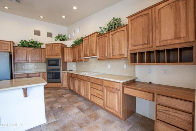 kitchen featuring tasteful backsplash, oven, built in microwave, white electric cooktop, and freestanding refrigerator