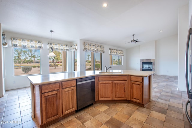 kitchen featuring stainless steel dishwasher, light countertops, a sink, and a tile fireplace