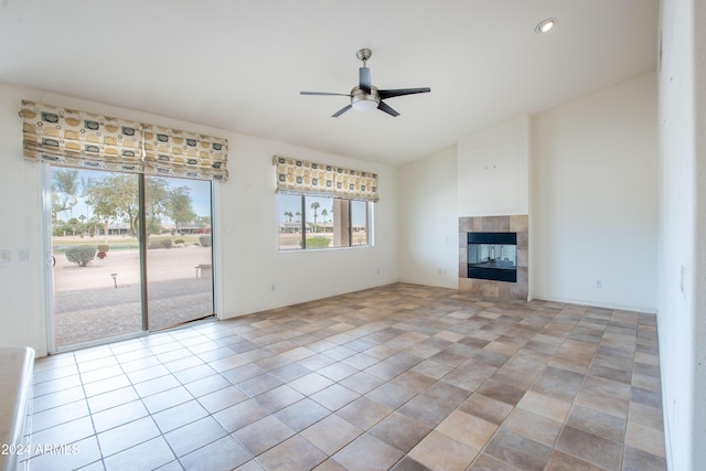 unfurnished living room featuring light tile patterned floors, lofted ceiling, a ceiling fan, and a tile fireplace