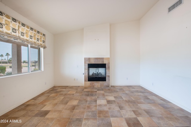 unfurnished living room with a tiled fireplace, visible vents, and baseboards