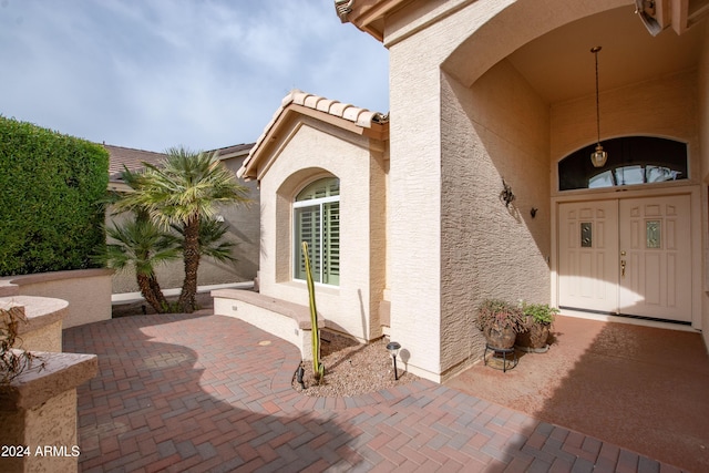 view of exterior entry featuring stucco siding, a patio, and a tile roof