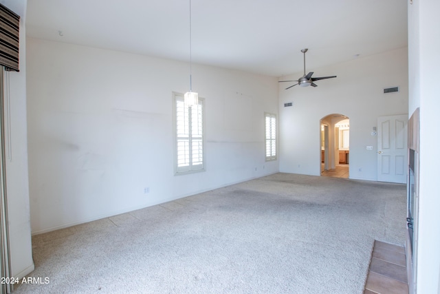 spare room featuring visible vents, ceiling fan, carpet floors, a high ceiling, and arched walkways