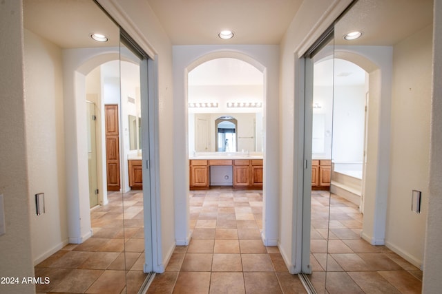 corridor featuring visible vents, baseboards, light tile patterned flooring, recessed lighting, and a sink