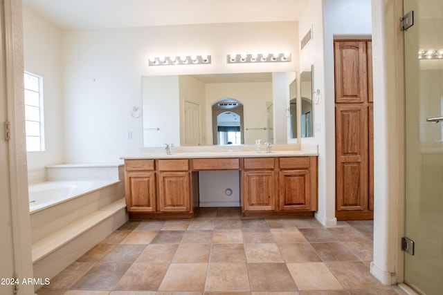 bathroom featuring visible vents, a sink, a shower stall, double vanity, and a bath