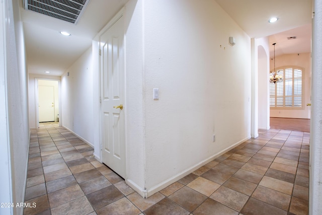 hallway with a notable chandelier, visible vents, recessed lighting, and arched walkways