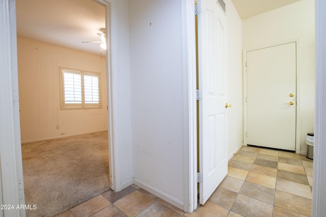 hallway featuring visible vents, light colored carpet, and baseboards