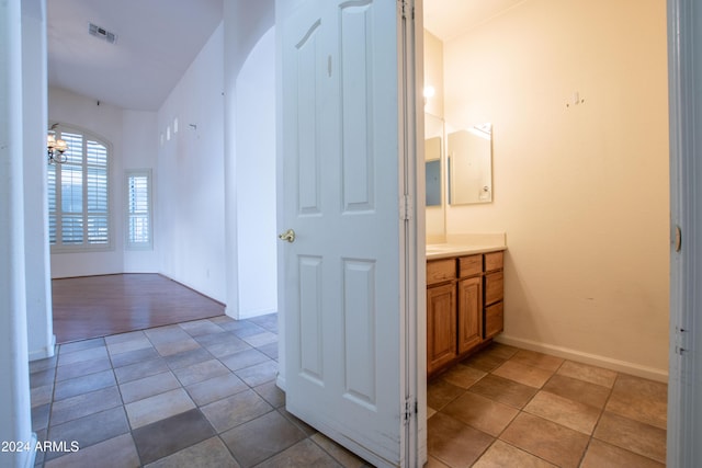 bathroom featuring vanity, baseboards, visible vents, tile patterned flooring, and a chandelier