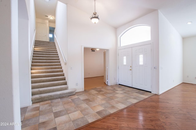 entryway featuring high vaulted ceiling, stairs, light wood-type flooring, and baseboards