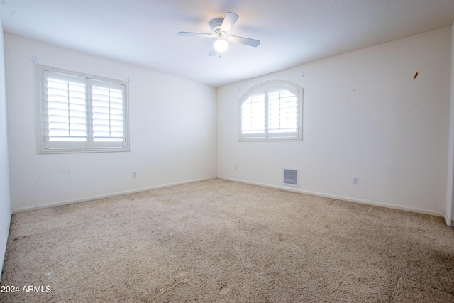 carpeted empty room with visible vents, baseboards, and a ceiling fan