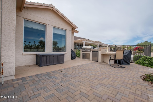 view of patio featuring a grill, fence, and an outdoor kitchen