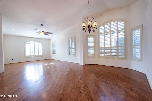 empty room featuring ceiling fan with notable chandelier, lofted ceiling, wood finished floors, and visible vents