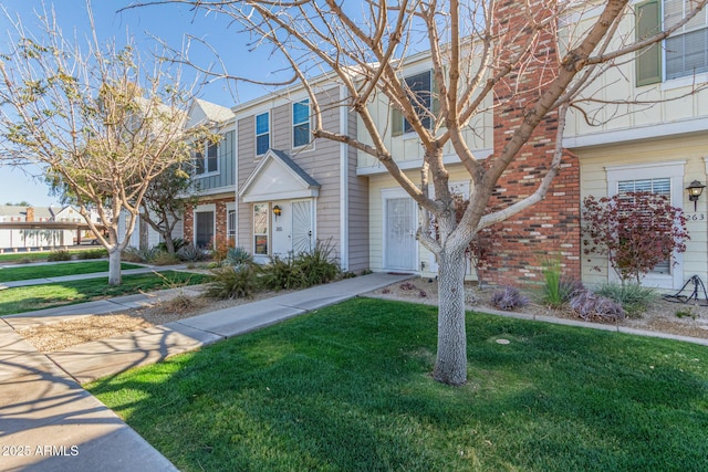 multi unit property with a front yard and brick siding