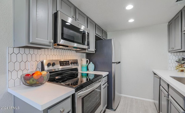 kitchen with appliances with stainless steel finishes, gray cabinets, and visible vents