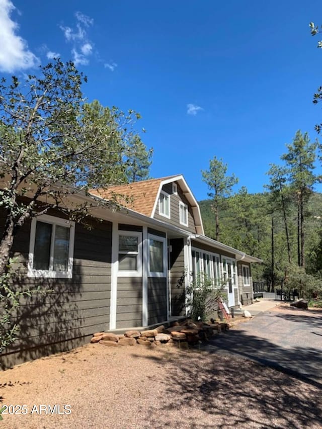 4405 N Mogollon Dr, Pine, AZ 85544 - view of property exterior with a gambrel roof, a sunroom, roof with shingles, and driveway