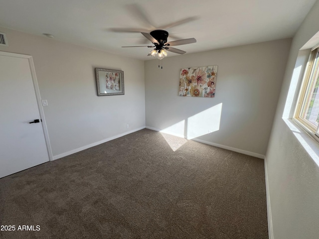 spare room featuring ceiling fan and dark carpet