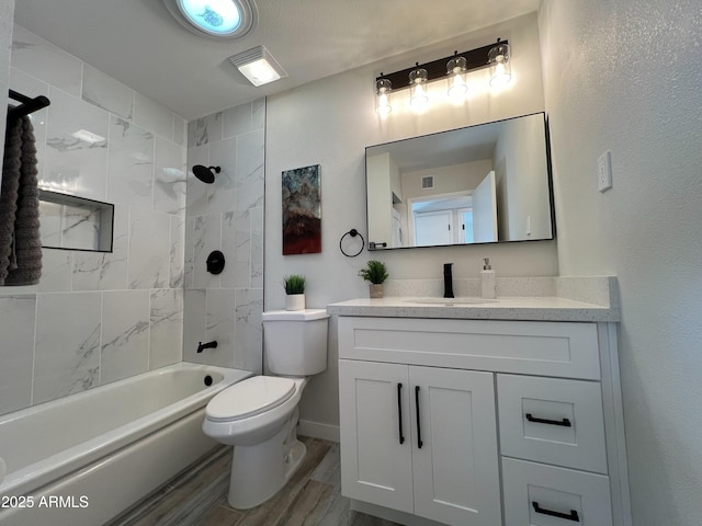 full bathroom with vanity, tiled shower / bath combo, hardwood / wood-style flooring, and toilet