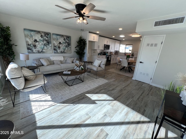 living room with ceiling fan and light hardwood / wood-style flooring